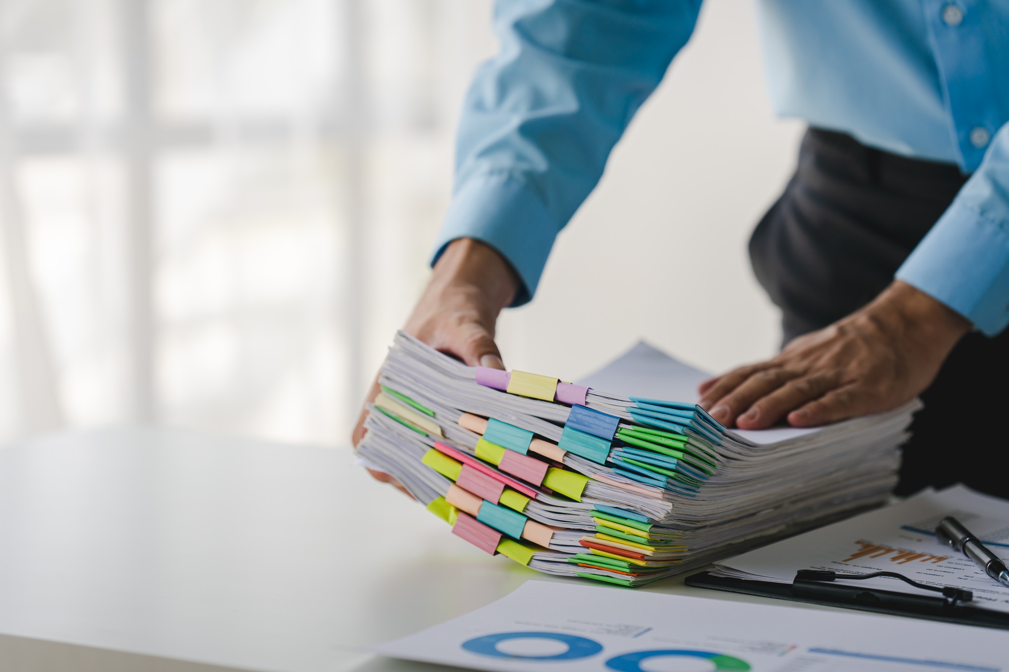 Businessman working on stacks of documents to search for information and check documents on office d